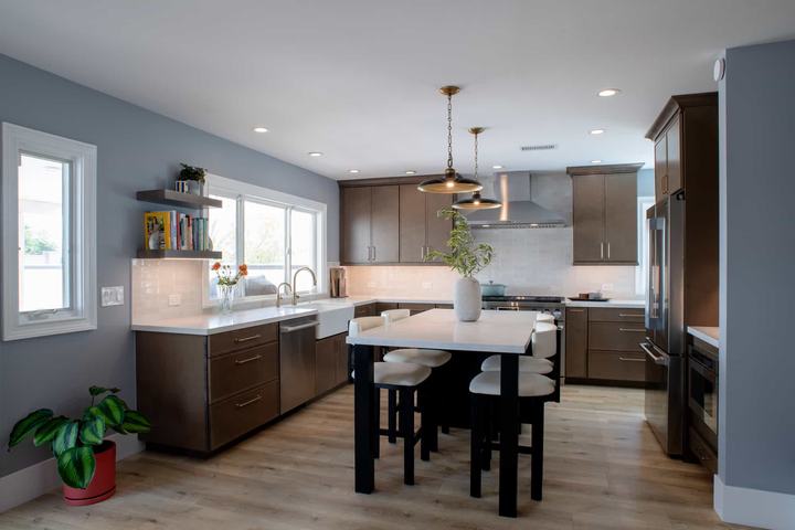 Remodeled kitchen with warm brown shaker cabinetry, a quartz-topped island, and light oak flooring
