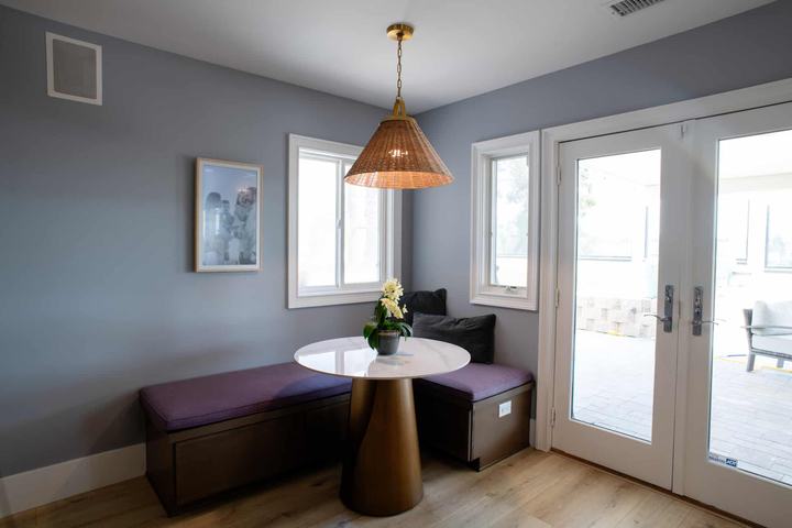 Built-in banquette with storage benches, a round marble-look table, and a woven rattan pendant beside the patio doors