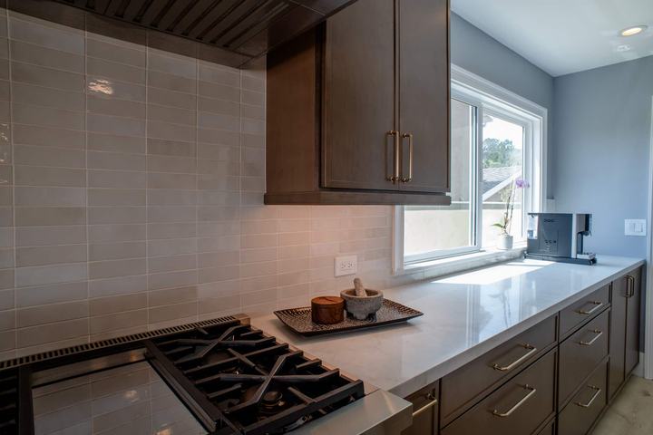Range wall with the ceramic tile backsplash, a wood hood surround, and a coffee station by the window