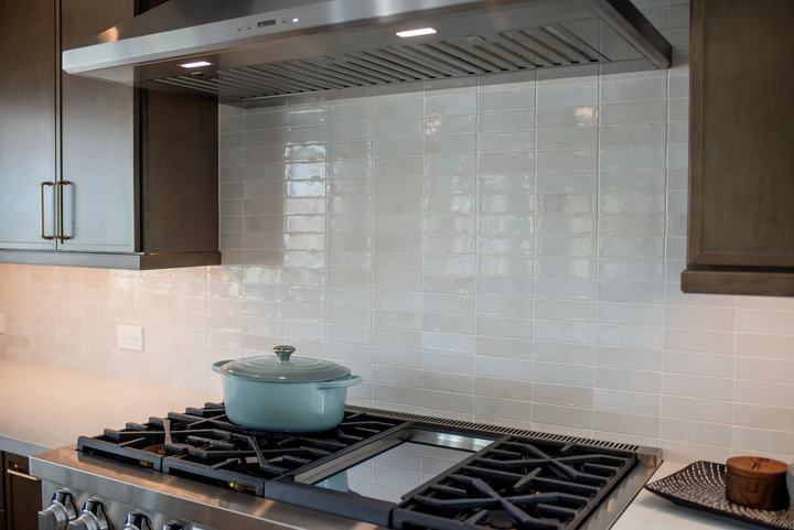 Stainless hood centered over the range with ceramic tile running full height behind it