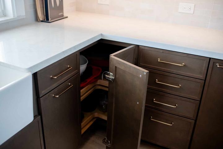 Blind corner cabinet opened to show lazy Susan storage beside the farmhouse sink