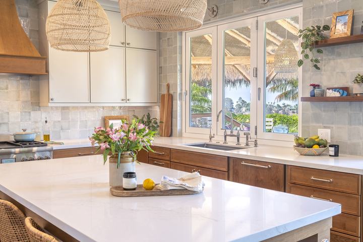 Quartz island vignette looking to sink wall, woven pendants, Painted Harbor uppers, Cherry Amber lowers, and full-height ceramic backsplash