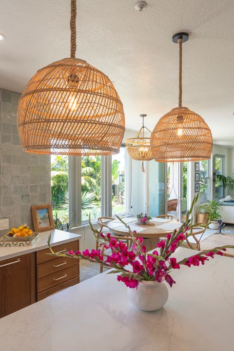 Woven dome pendants over quartz island with bright pink florals, dining nook, and floor-to-ceiling windows