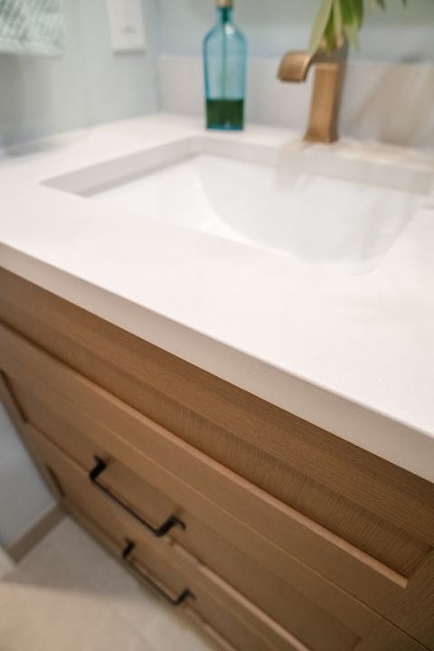 Close view of the white vanity top's square edge over the wood drawer fronts