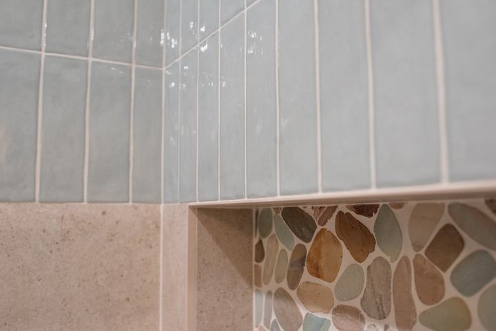 Angled view of undulated blue ceramic stacked vertically over the porcelain, niche edge below