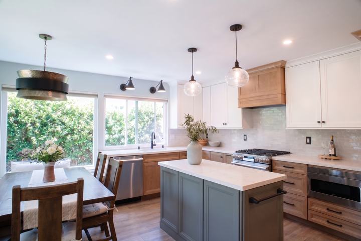 Kitchen with a green island, maple cabinetry, and white uppers beside the banquette table