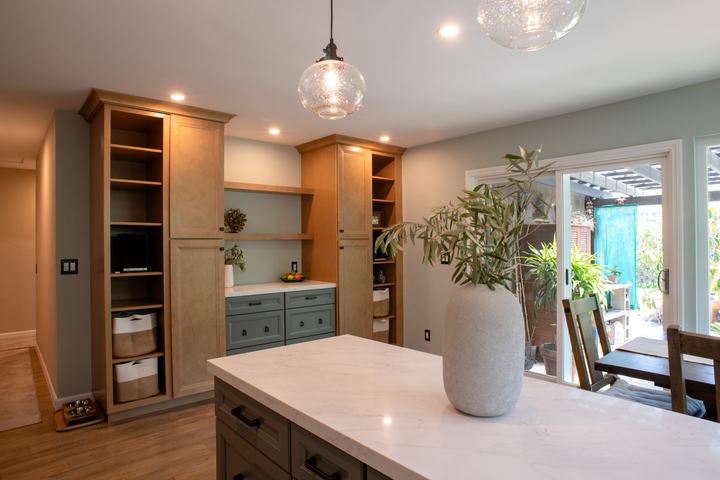 Two tall maple pantries flanking a green buffet with open display shelves between