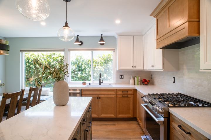 Maple base cabinets along the sink run with the gas range and wood hood on the far wall