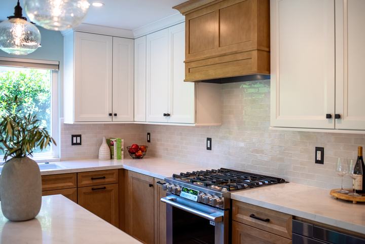 Corner of the kitchen showing white uppers, the wood hood, and the range below