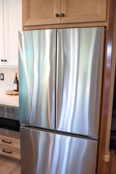 Stainless French door refrigerator set into the maple cabinet surround