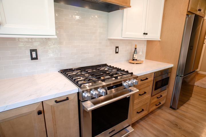 Range and microwave drawer set into the maple cabinet run beside the refrigerator