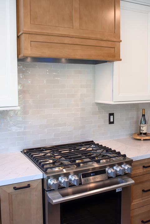 Wood hood surround above the gas range with gloss porcelain tile running behind it
