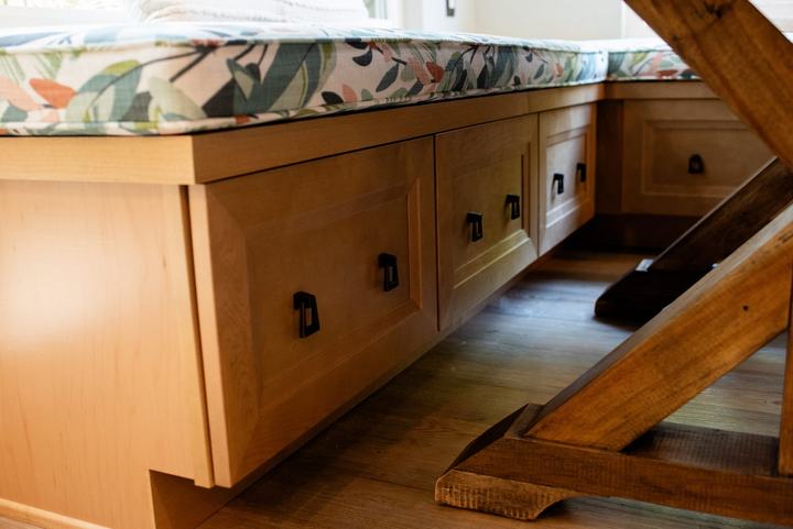 Maple storage fronts beneath the banquette bench with dark drop pulls