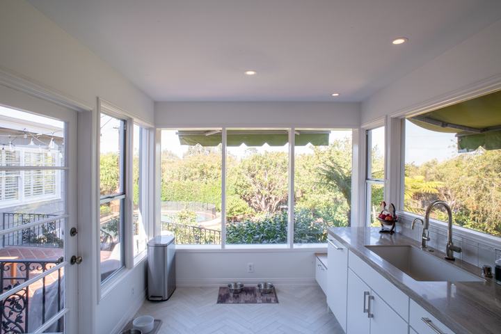 Corner of tall windows overlooking the yard and pool, with the sink run on the right