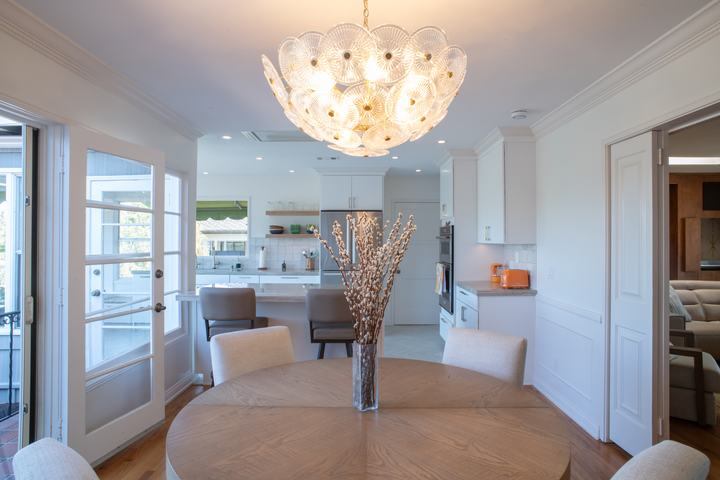 Dining table under a glass chandelier, opening straight into the kitchen