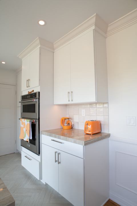 Wall oven and microwave combination beside a short counter with tile backsplash