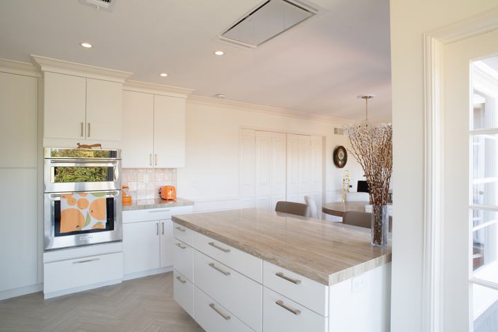 Island with drawer storage below a ceiling-mounted range hood, dining room beyond