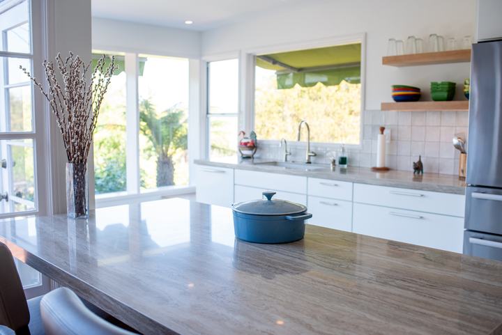 Blue Dutch oven sitting on the porcelain island surface, sink wall in the background