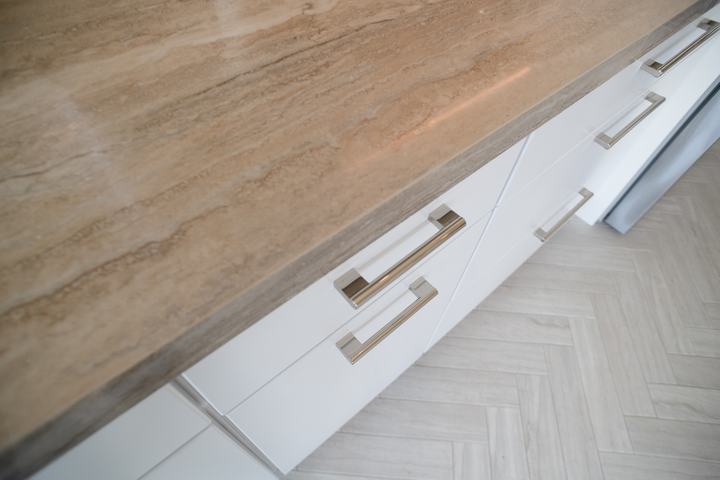 Overhead view of the countertop edge and stainless pulls above the herringbone floor