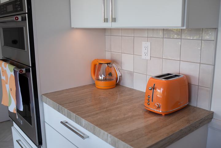 Orange kettle and toaster on a porcelain counter beside the wall oven