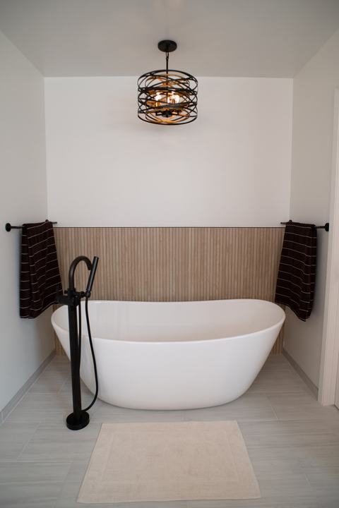 Freestanding soaking tub with a floor-mounted tub filler and towel bars on each side