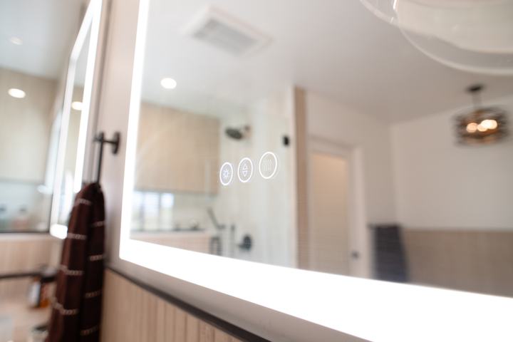 Touch controls glowing on the face of a lighted mirror