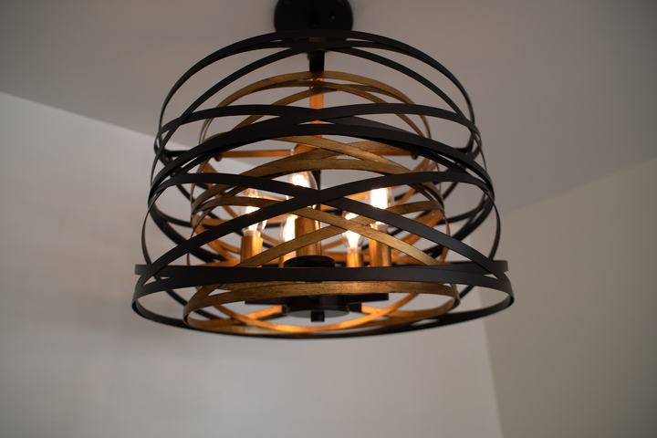 Drum chandelier with crisscrossing black and gold metal bands