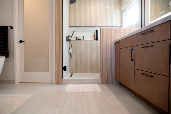 Shower entrance beside a frosted glass door to the water closet