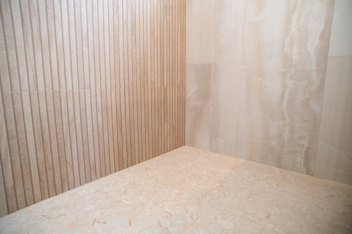 Hexagon porcelain mosaic shower floor meeting slat and onyx-look wall tile
