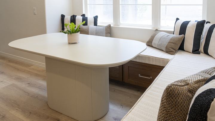 Detail of fluted pedestal table beside chevron-textured banquette cushions and quartz counter edge