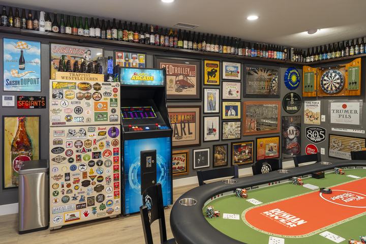 Arcade cabinet and stickered fridge along gallery wall