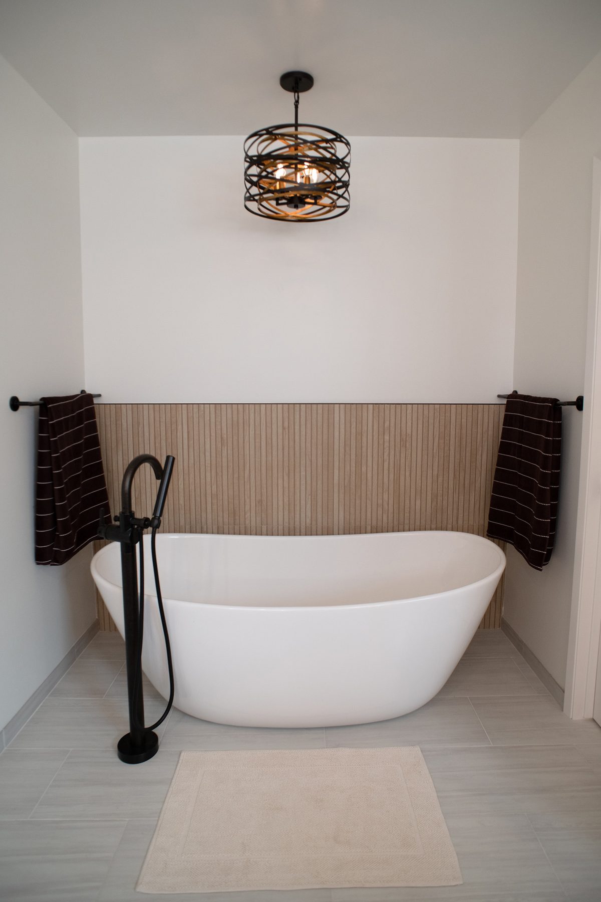 Freestanding soaking tub beneath a chandelier in a remodeled Point Loma master bath