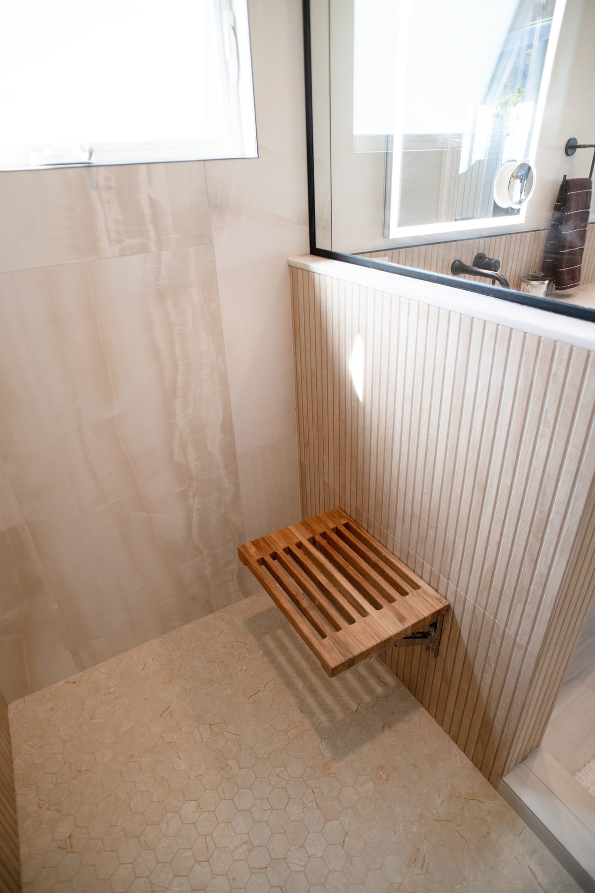 Fold-down teak shower seat in the walk-in shower of a Point Loma master bath
