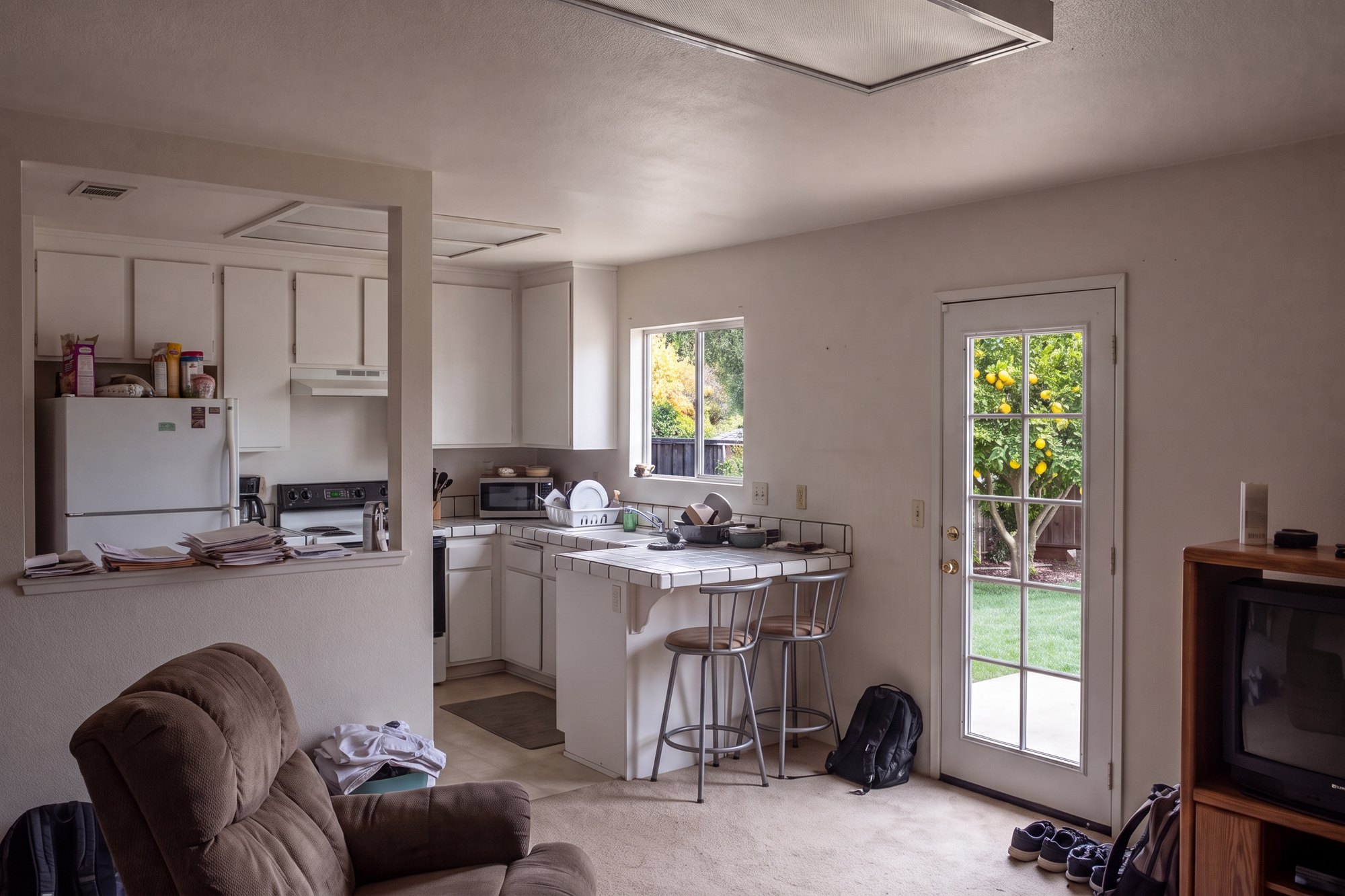 Before: a cramped 1990s kitchen and family room with a low ceiling and a single patio door
