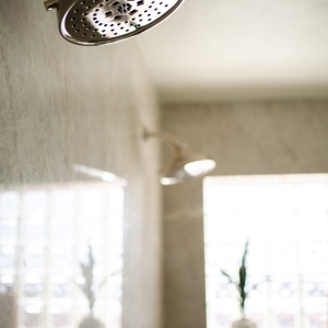 Close-up of Brizo Invari multi-function showerhead against quartzite wall, soft focus background
