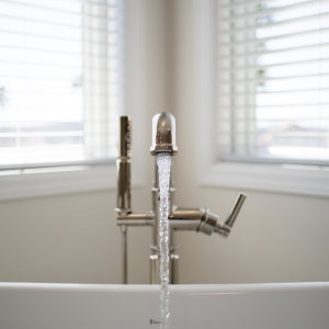 Close-up of polished-nickel Brizo tub filler splashing water in the BainUltra Evanescence tub