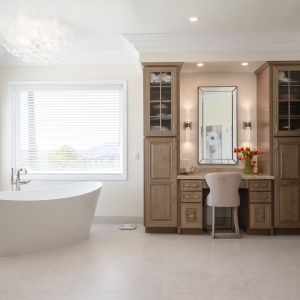 Freestanding micro-bubble tub under bubble-glass chandelier next to makeup vanity and linen towers