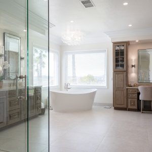 Wide shot of tub, vanity and slab-wall shower reflected in frameless glass enclosure