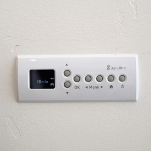 BainUltra digital control panel for the heated micro-bubble bathtub mounted on the bathroom wall.