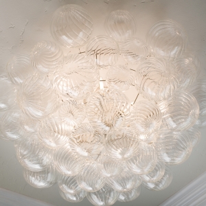Bubble chandelier centered on cove ceiling in the luxurious primary bath.