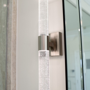 Sparkling crystal-rod wall sconce providing ambient lighting by the vanity mirror.