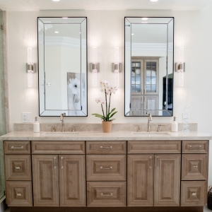 Symmetrical front view of twin sinks, polished-nickel faucets and orchid centerpiece on quartzite countertop.
