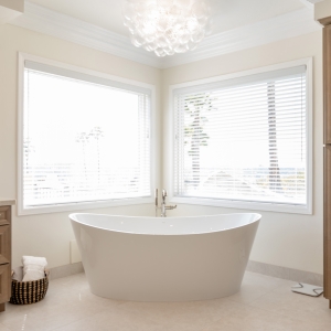 Freestanding oval soaking tub nestled in a windowed corner beneath a glowing glass-bubble chandelier.