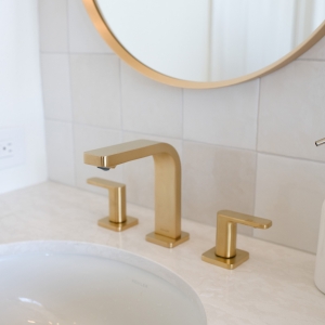 Brushed-gold oval faucet set above polished quartz undermount sink.
