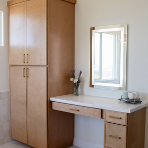 Built-in makeup desk beside full-height linen tower cabinetry.