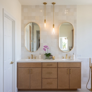 Angle showing vanity and linen tower with coordinated gold hardware.