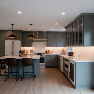 Wide view of sage kitchen and quartz island