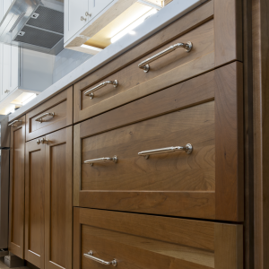 Low-angle detail of walnut drawer fronts with polished-chrome pulls and soft under-cabinet LED lighting