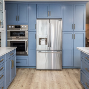 Built-in fridge flanked by tall blue pantry cabinets