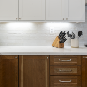 Detail of walnut base drawers with chrome pulls, white subway backsplash, and quartz countertop